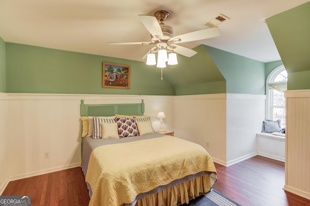 bedroom with visible vents, wainscoting, ceiling fan, dark wood-style flooring, and vaulted ceiling