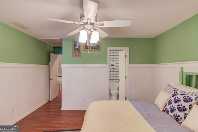 bedroom with dark wood-style flooring, wainscoting, ceiling fan, and visible vents