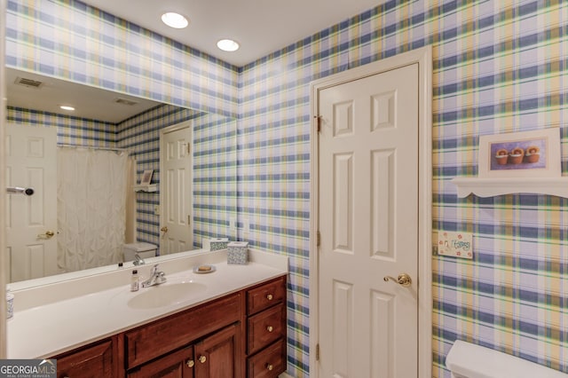 full bath featuring toilet, a shower with shower curtain, visible vents, vanity, and wallpapered walls