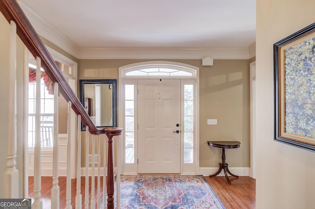 foyer entrance featuring ornamental molding, light wood finished floors, stairs, and baseboards