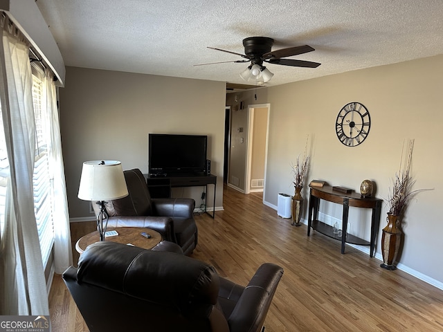 living room with hardwood / wood-style flooring, ceiling fan, and a textured ceiling