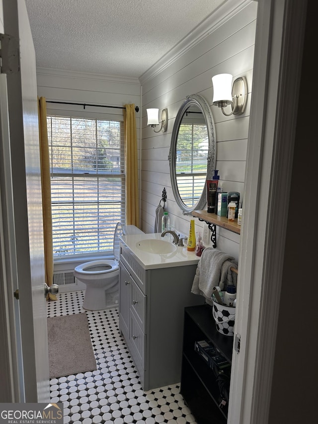 bathroom featuring a textured ceiling, toilet, crown molding, and plenty of natural light