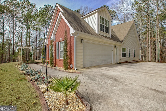 view of side of home featuring brick siding, an attached garage, roof with shingles, and concrete driveway