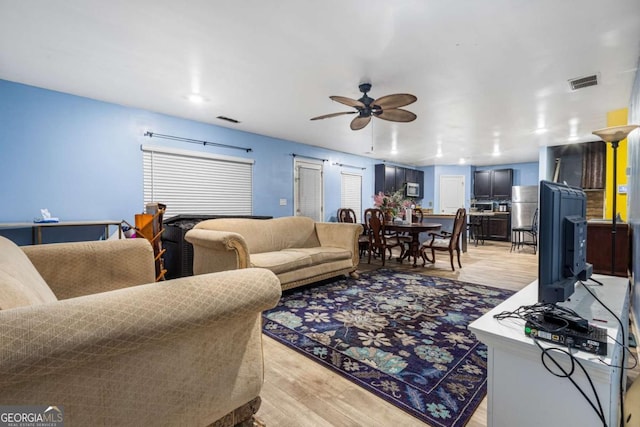 living room with ceiling fan and light hardwood / wood-style floors