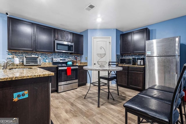 kitchen featuring light hardwood / wood-style floors, stainless steel appliances, tasteful backsplash, and sink