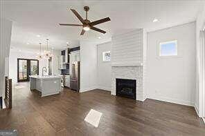 unfurnished living room featuring ceiling fan, a large fireplace, and dark hardwood / wood-style floors