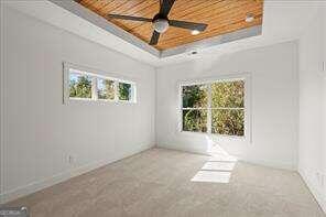 unfurnished room featuring a tray ceiling, wooden ceiling, and ceiling fan