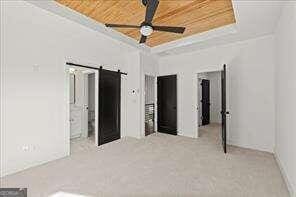 unfurnished bedroom featuring a tray ceiling, ornamental molding, wood ceiling, and ceiling fan