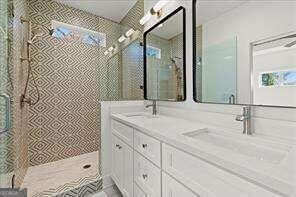 bathroom with vanity and tiled shower