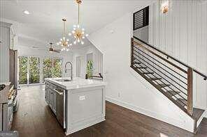 kitchen with a chandelier, dishwasher, dark hardwood / wood-style floors, decorative light fixtures, and a kitchen island with sink