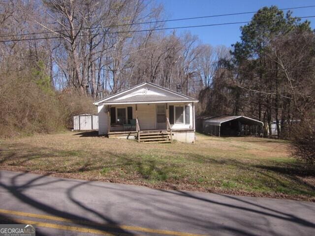 bungalow-style house with a front lawn, a porch, and a carport