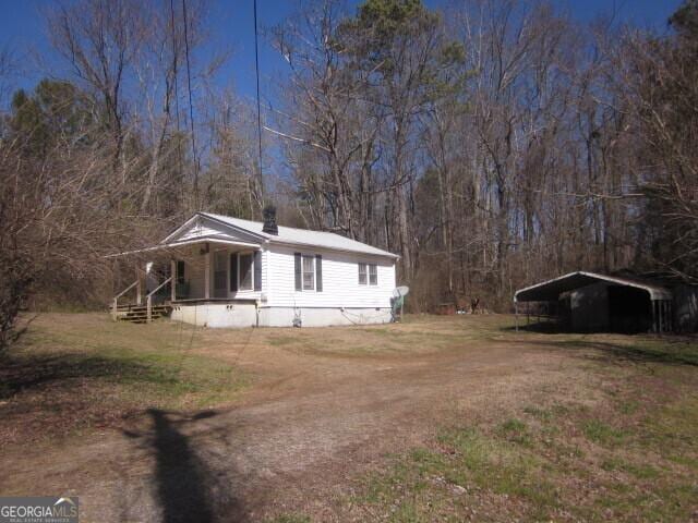 view of side of property with driveway, a carport, a porch, and a lawn