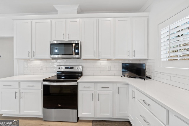 kitchen featuring appliances with stainless steel finishes, light hardwood / wood-style flooring, crown molding, backsplash, and white cabinetry