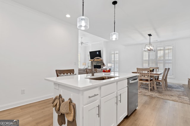 kitchen featuring an island with sink, stainless steel dishwasher, pendant lighting, sink, and white cabinetry