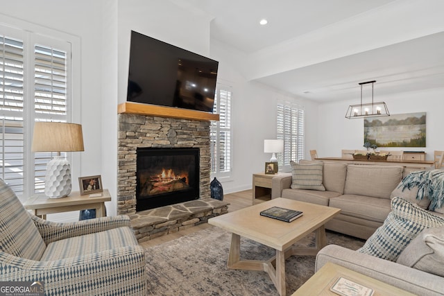 living room with a fireplace, ornamental molding, a notable chandelier, and wood-type flooring