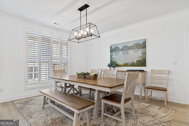 dining space with light hardwood / wood-style flooring and crown molding