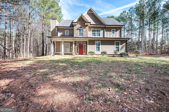 view of front of property with board and batten siding, stone siding, covered porch, and a chimney