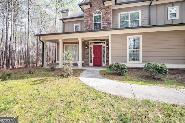 view of front of property with board and batten siding, stone siding, covered porch, and a front lawn