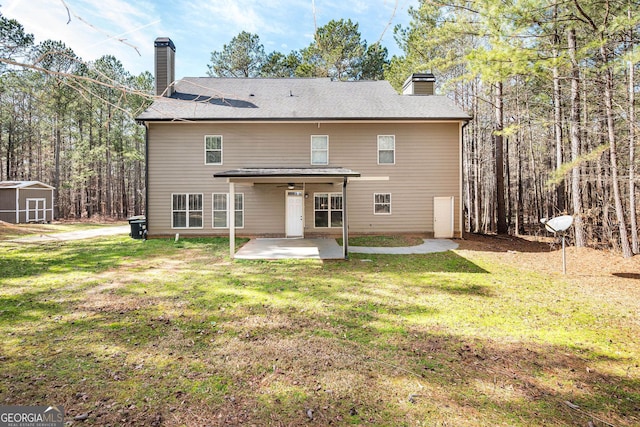 rear view of house featuring a yard, a chimney, a storage shed, and a patio