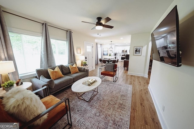 living room with baseboards, light wood-style flooring, and a ceiling fan