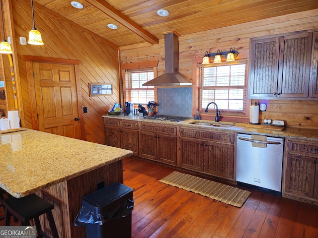 kitchen with hanging light fixtures, a kitchen breakfast bar, wall chimney exhaust hood, stainless steel appliances, and sink