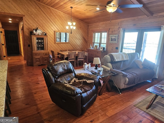 living room with ceiling fan with notable chandelier, dark hardwood / wood-style flooring, wooden ceiling, and wooden walls