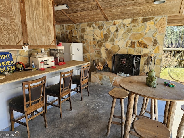 kitchen with white appliances, a stone fireplace, and wood ceiling