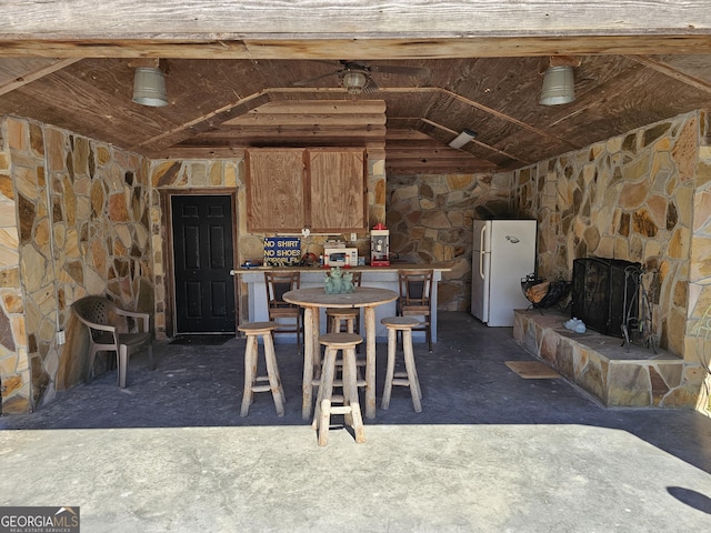 dining space featuring a stone fireplace and lofted ceiling