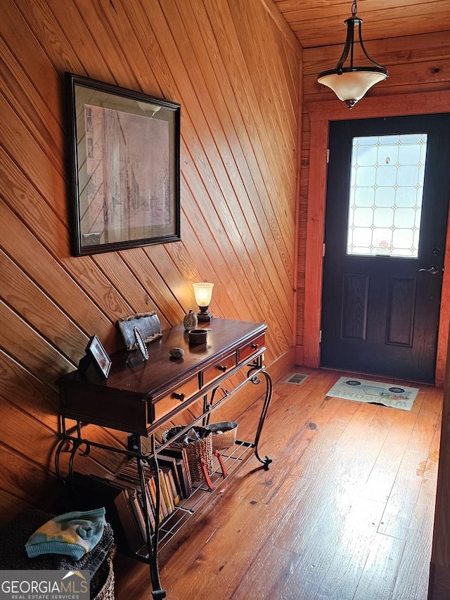 foyer with hardwood / wood-style flooring and wooden walls