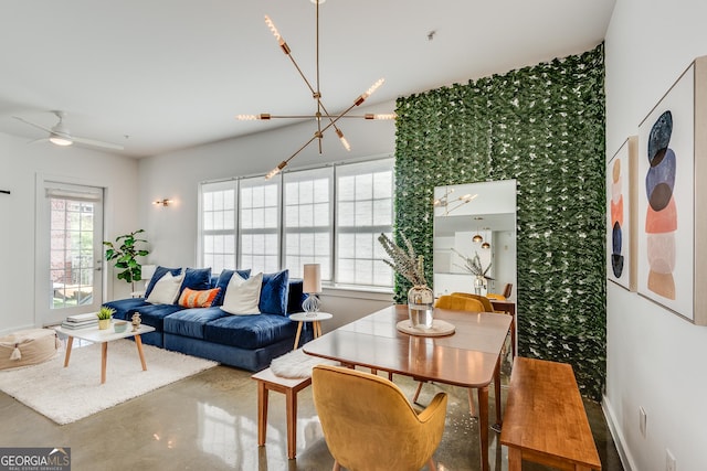 living area featuring a healthy amount of sunlight, finished concrete floors, baseboards, and ceiling fan with notable chandelier