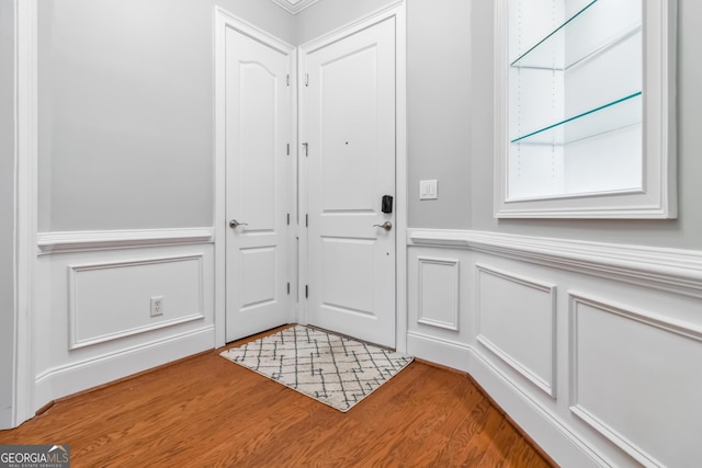 doorway to outside featuring a decorative wall, light wood-type flooring, and a wainscoted wall