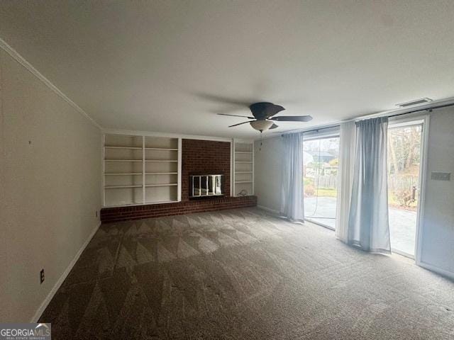 unfurnished living room with built in shelves, carpet, crown molding, a brick fireplace, and baseboards