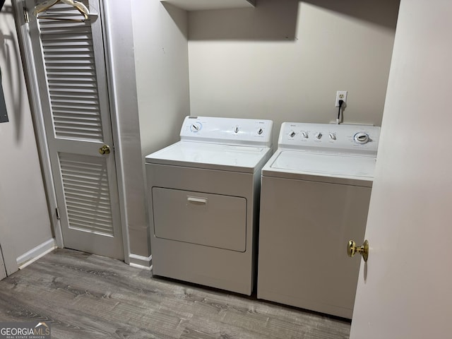 washroom featuring laundry area, baseboards, washing machine and clothes dryer, and wood finished floors