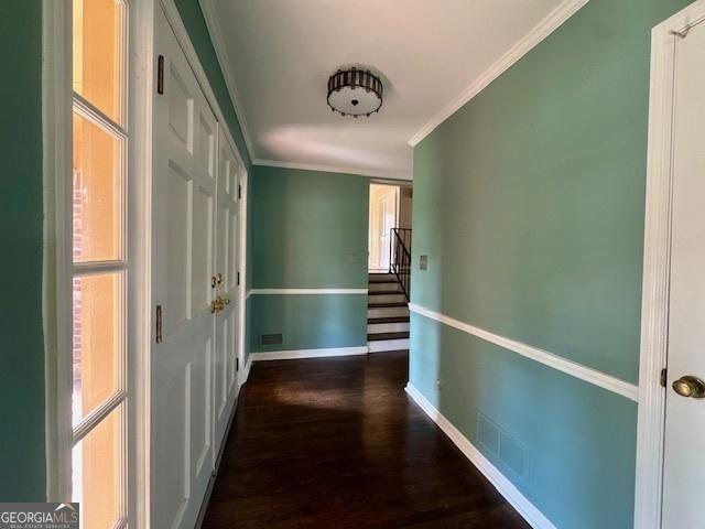 corridor featuring visible vents, baseboards, dark wood-style flooring, stairs, and crown molding