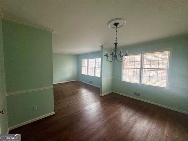 unfurnished dining area featuring baseboards, visible vents, dark wood-style floors, an inviting chandelier, and crown molding