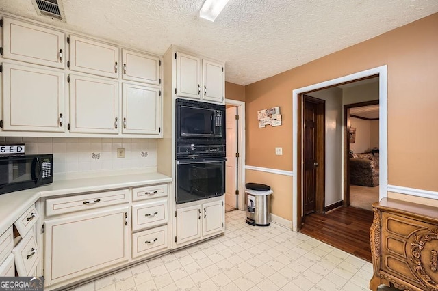 kitchen with black appliances, a textured ceiling, and decorative backsplash