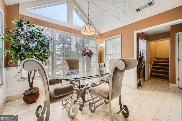 dining room with vaulted ceiling and a textured ceiling