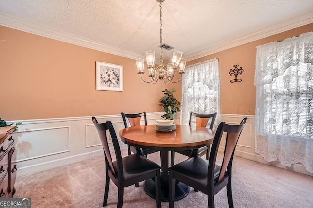 dining area featuring an inviting chandelier, a textured ceiling, light colored carpet, and ornamental molding