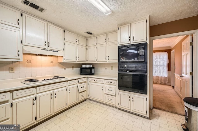 kitchen featuring cream cabinets, black appliances, a textured ceiling, and backsplash