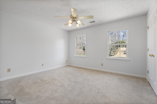 unfurnished room featuring light colored carpet, ceiling fan, visible vents, and a textured ceiling