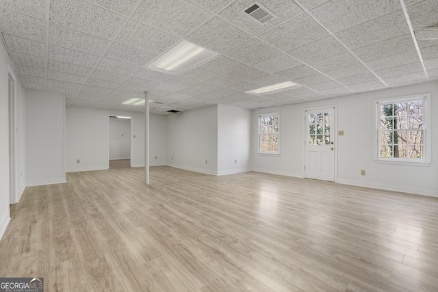 below grade area featuring light wood-style floors, baseboards, visible vents, and a wealth of natural light