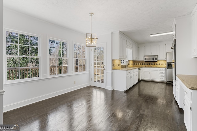 kitchen with dark wood-style flooring, baseboards, white cabinets, appliances with stainless steel finishes, and decorative backsplash