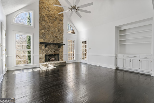 unfurnished living room featuring ceiling fan, high vaulted ceiling, a fireplace, built in features, and dark wood finished floors