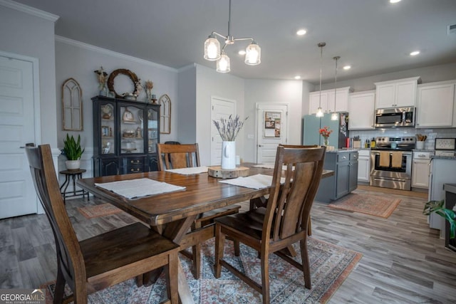 dining room with light wood-type flooring, an inviting chandelier, and crown molding