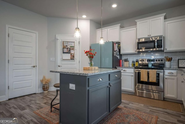 kitchen featuring a center island, stainless steel appliances, white cabinets, hardwood / wood-style flooring, and tasteful backsplash