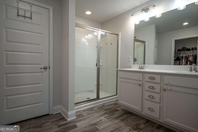 bathroom featuring an enclosed shower, vanity, and wood-type flooring