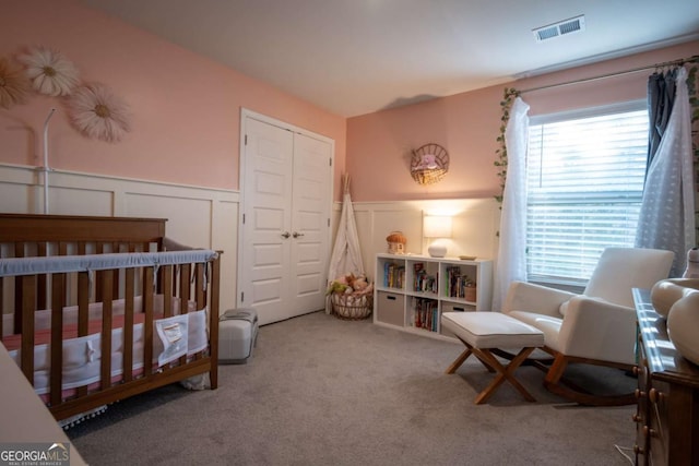 carpeted bedroom with a closet and a nursery area