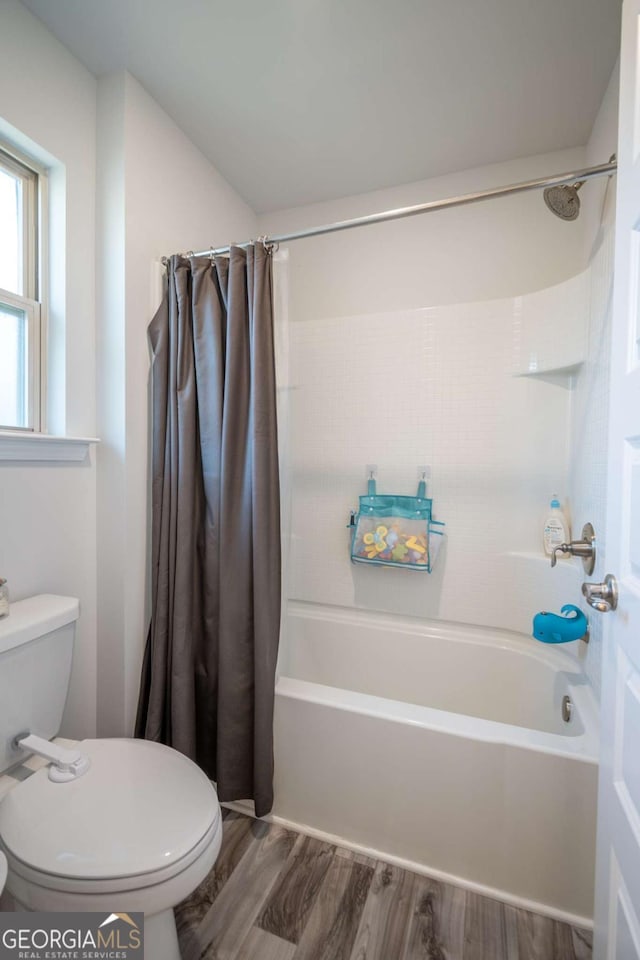 bathroom featuring shower / bathtub combination with curtain, wood-type flooring, and toilet