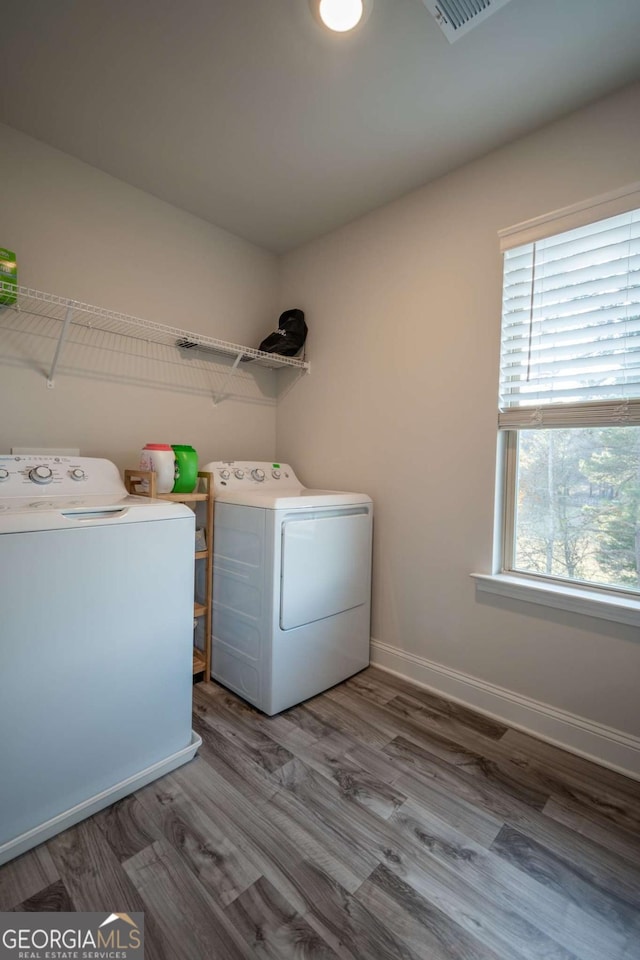 laundry room with washer and dryer and wood-type flooring