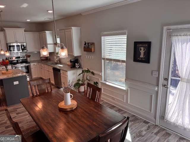 dining room featuring ornamental molding, sink, and light hardwood / wood-style floors